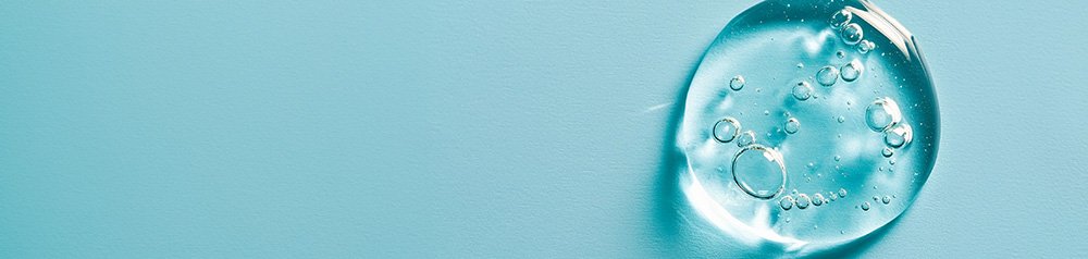 Kropla gęstego przezroczystego żelu na niebieskim tle